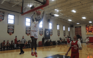 Dunking basketball during youth sports game at Prep Athletics gymnasium.