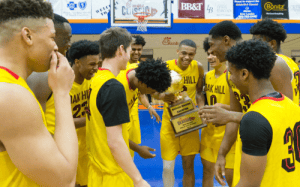 Vibrant youth basketball team in yellow jerseys celebrating victory with trophy in a gymnasium.