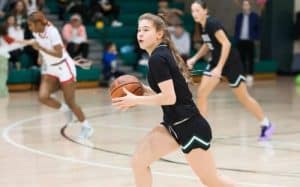 Youth girls playing basketball during a sports practice at an indoor gym.