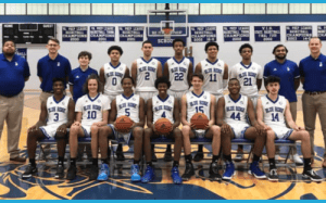 Blue Ridge varsity basketball team posing in gym with basketballs and coaches