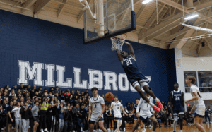 Millbrook basketball player dunking during a home game with crowd cheering in the background