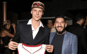 NBA draft night moment featuring a new Miami Heat player holding his jersey alongside Dan Poneman.