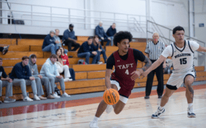 Taft basketball player drives past Williston defender during prep school game.