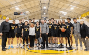 Tilton School boys basketball team and coaches posing together on the court during the NEPSAC prep basketball season.