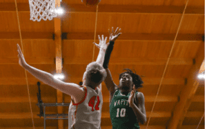 Winchendon School basketball player in green jersey taking a contested jump shot against defender during prep school game