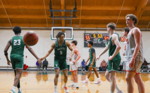 Winchendon School basketball players high-five during a close NEPSAC prep school game with scoreboard showing 55-54 score