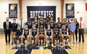 Hotchkiss School boys basketball team group photo with players, coaches, and staff in the gym.