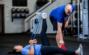 Tim DiFrancesco coaching an athlete through a resistance band recovery and mobility exercise.