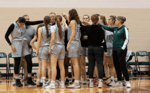 Western Reserve Academy girls basketball team huddles with coaches during a prep school game.