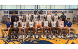 The Blue Ridge School basketball team poses for their official photo in the gym, wearing white uniforms and surrounded by championship banners.