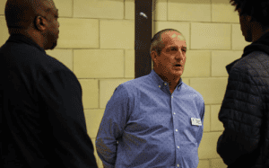 Coach Brian Fruscio of Canterbury School talks with parents and a player about prep school basketball decisions, focusing on reclassing and recruiting readiness.