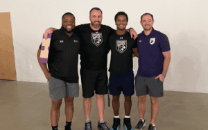 Perkiomen School basketball coaching staff stands together smiling after practice, showing teamwork, leadership, and unity within the prep basketball program.