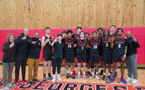 St. George’s School boys basketball team and coaches pose together after a season-ending victory in the gym.