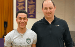 High school basketball player standing with a coach indoors, representing mentorship, guidance, and the transition toward college athletics.